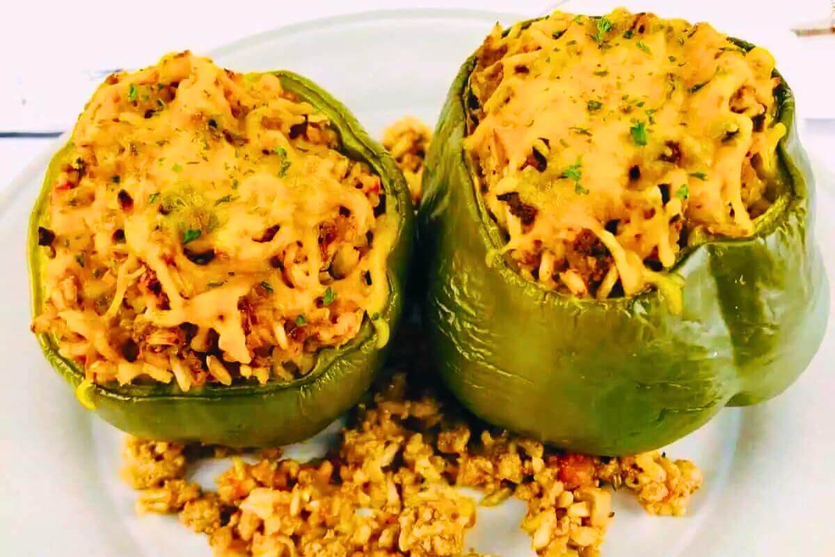 Two stuffed green peppers with cheese one top.