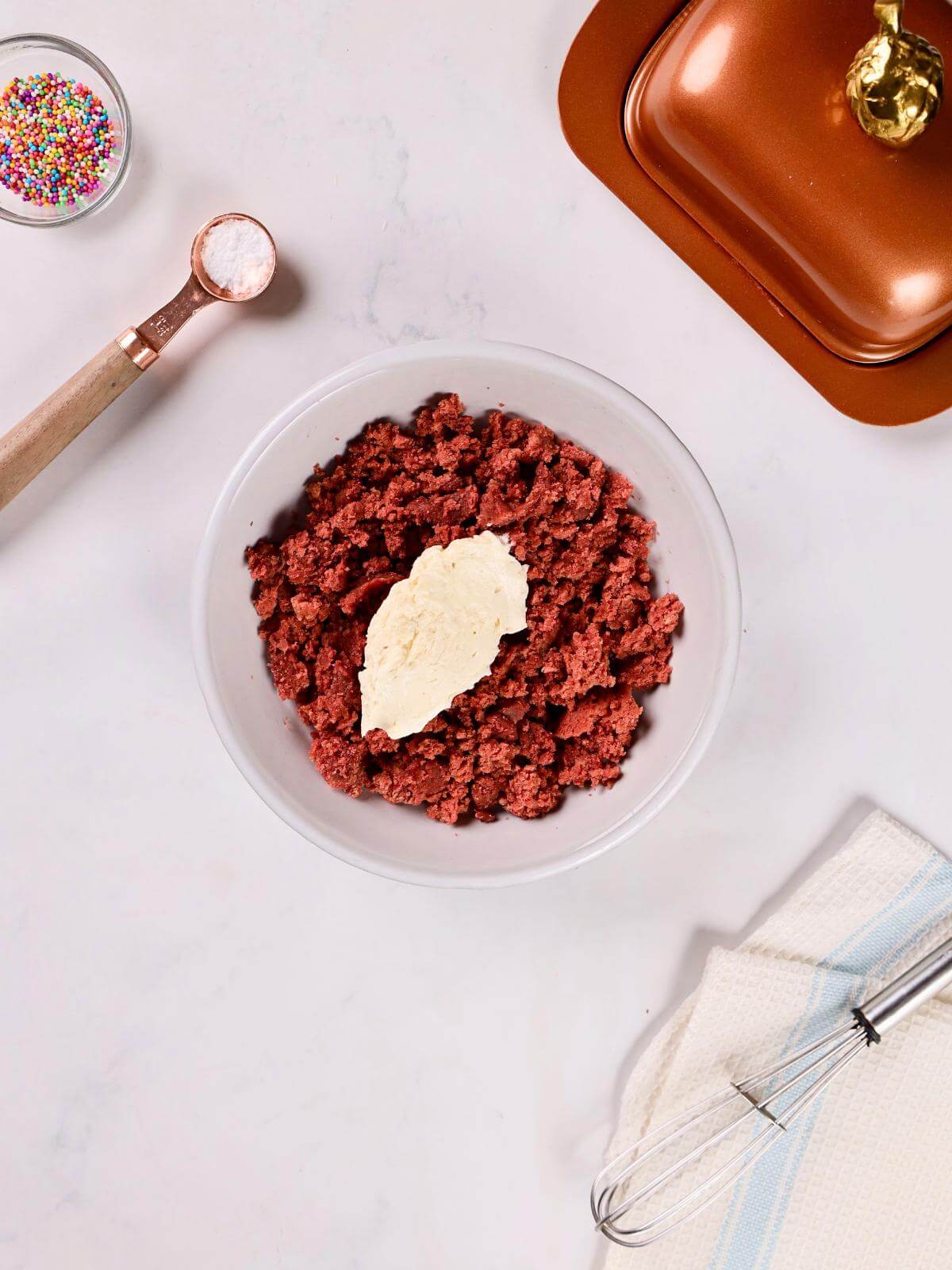 Crumbled red velvet cake and buttercream frosting in a bowl.