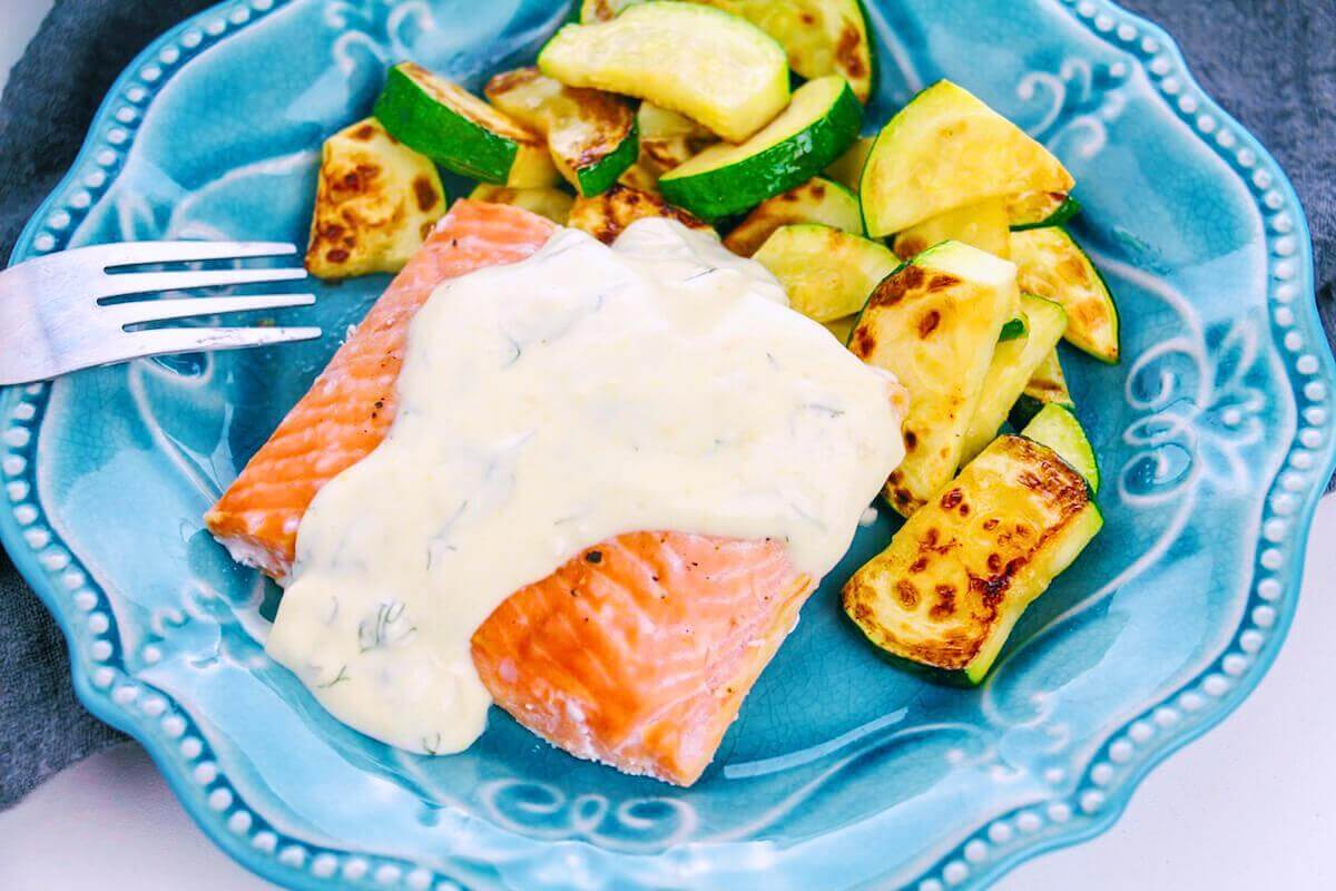 Baked salmon with creamy dill sauce on a plate.