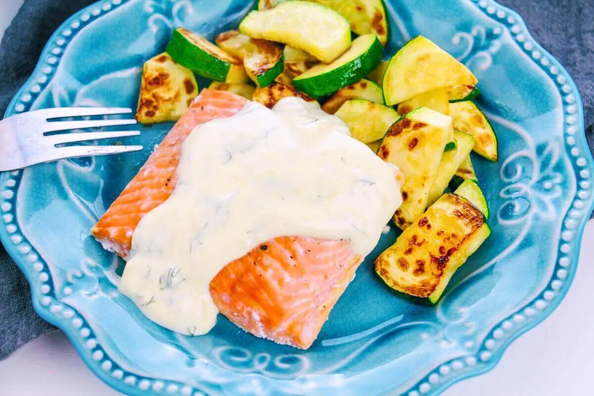 Baked salmon with creamy dill sauce on a plate.