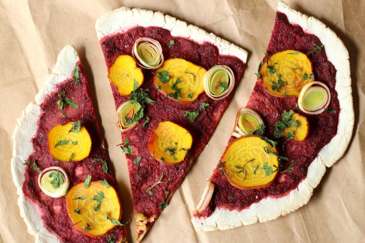 Slices of pizza with beet and leek toppings.