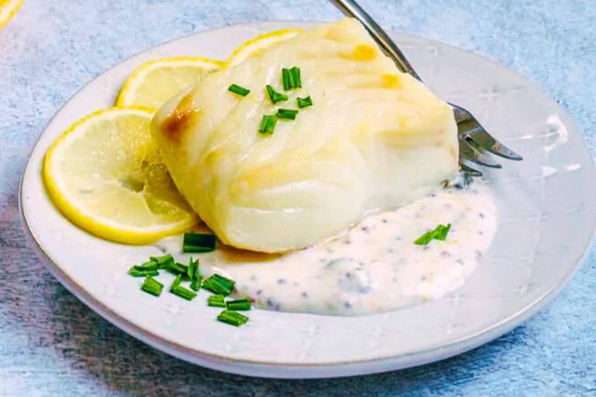 Cooked halibut with a lemon sauce on a plate.