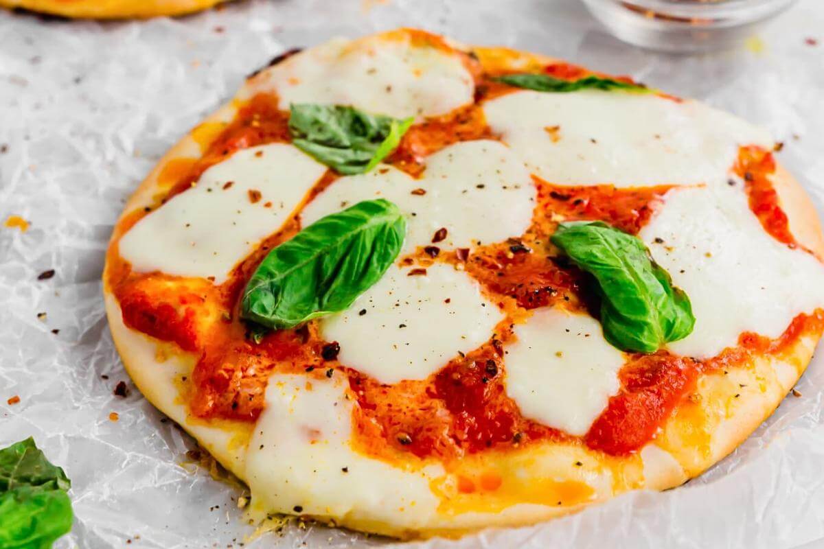 A cheese pizza with basil on top.