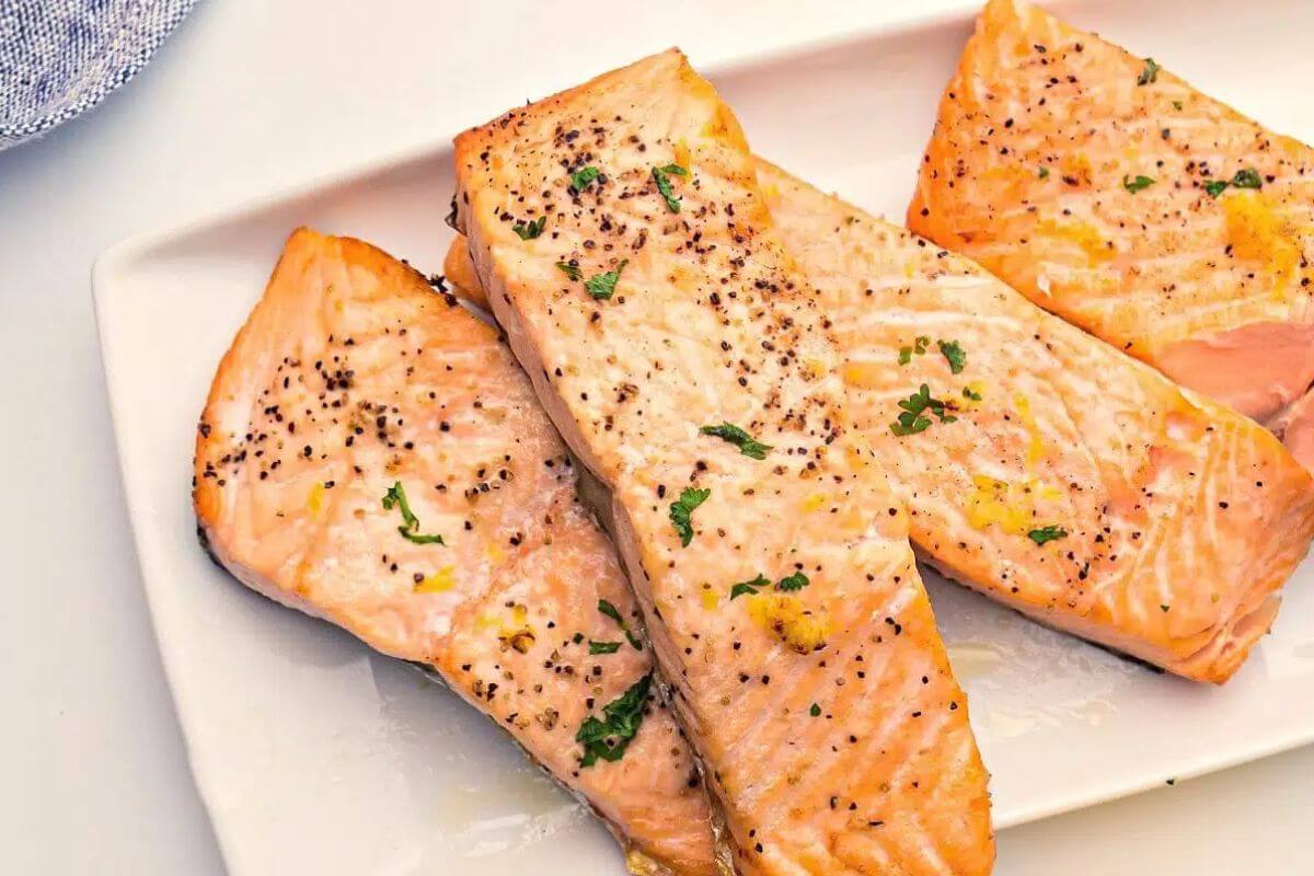 Four pieces of cooked salmon on a plate.