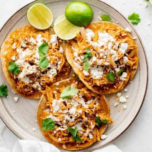 Shredded chicken tacos on a plate.