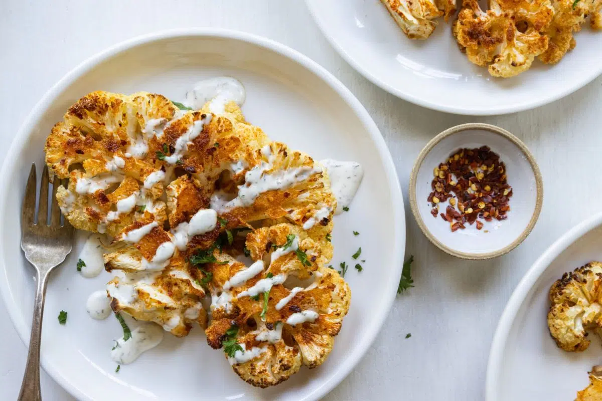 Super Easy Cauliflower Steak served with a vegan ranch dressing.
