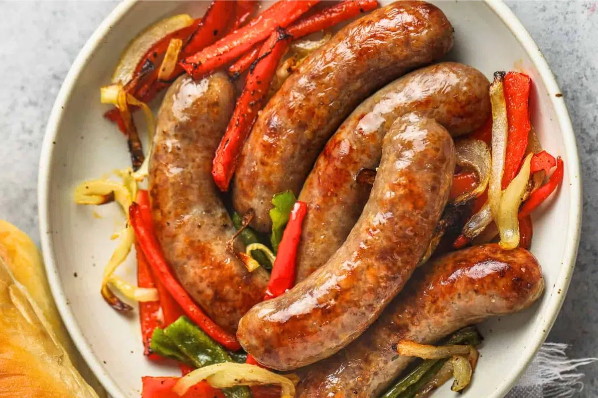 Brats With Peppers And Onions served on a plate.