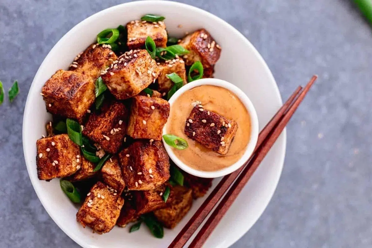 Crispy Pan Fried Tofu Bites served in a bowl with dipping sauce.
