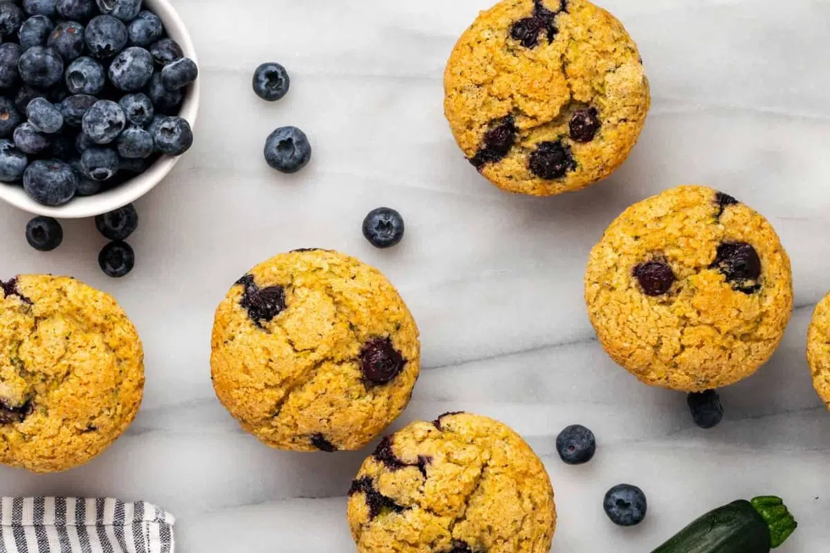 Easy Zucchini Blueberry Muffins alongside fresh blueberries.