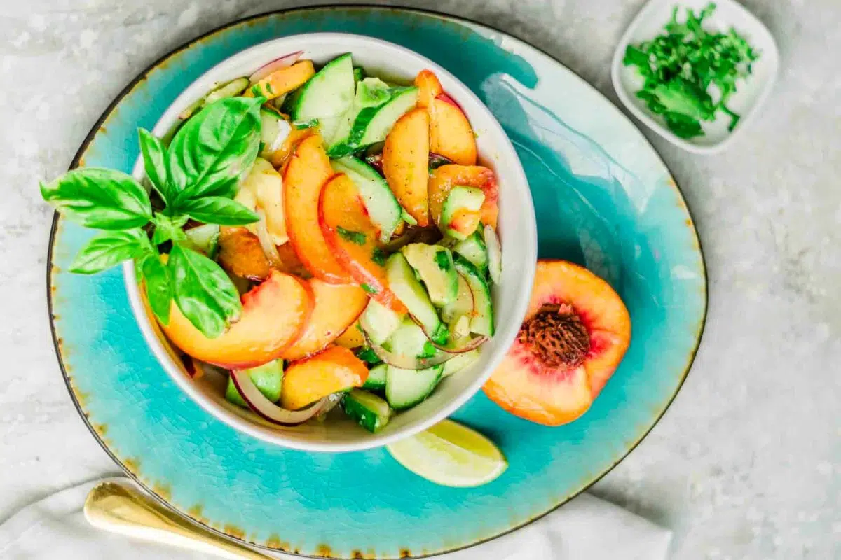 Fresh Peach Avocado Salad with Honey-Lime Dressing served on a blue plate.