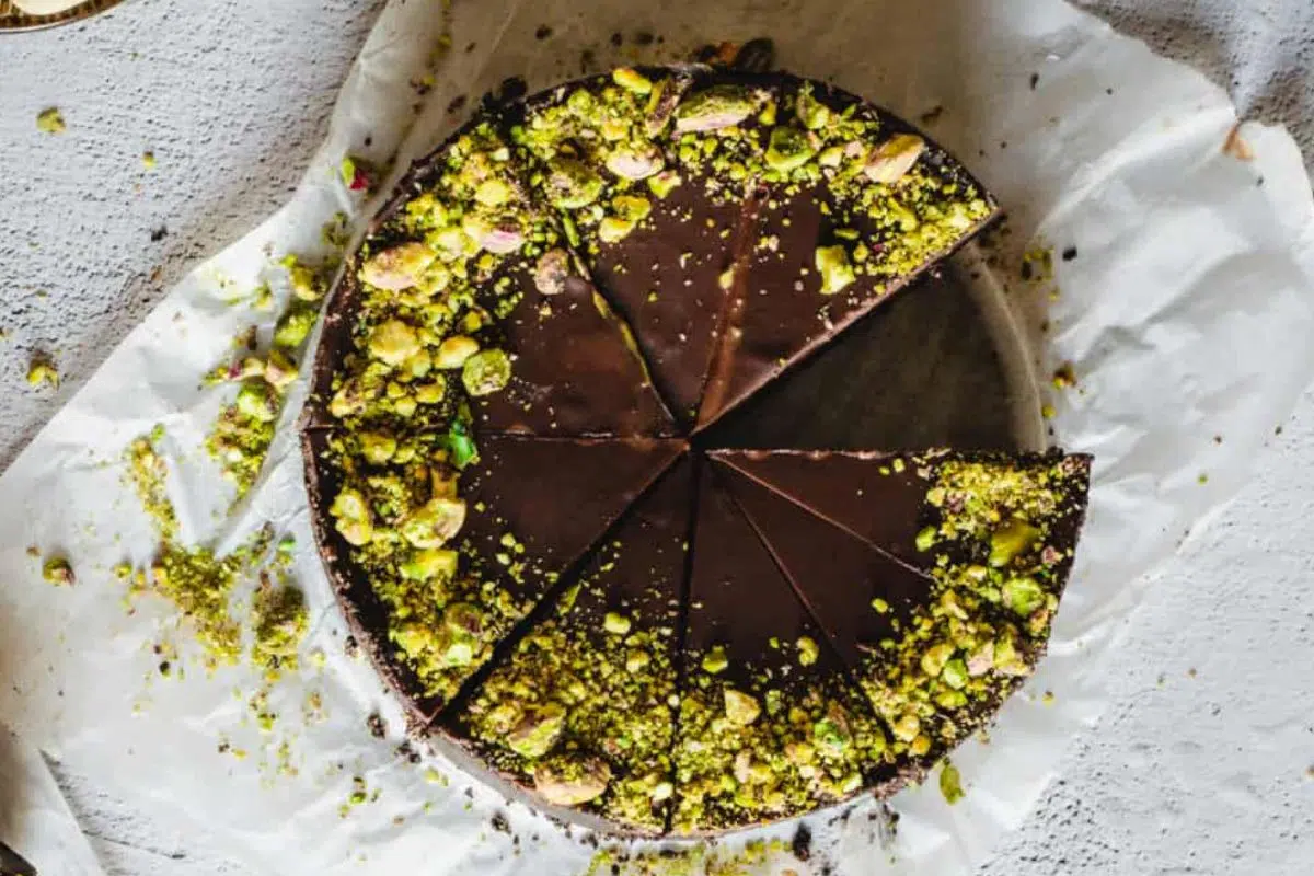 Non-Bake Chocolate pistachio cake topped with a thick vegan chocolate ganache and finished with a sprinkle of pistachio nuts.