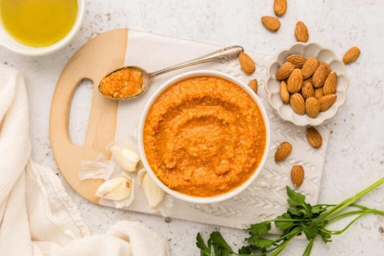Romesco Sauce served in a bowl alongside almonds.