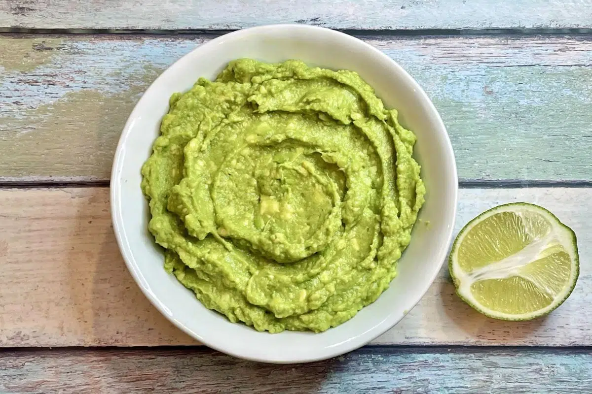 Easy 3-Ingredient Guacamole with a slice of lime.