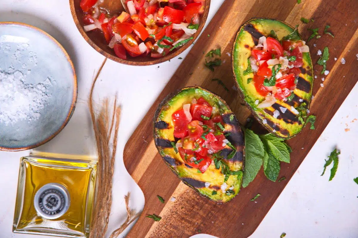 Grilled Stuffed Avocado on a wooden board.