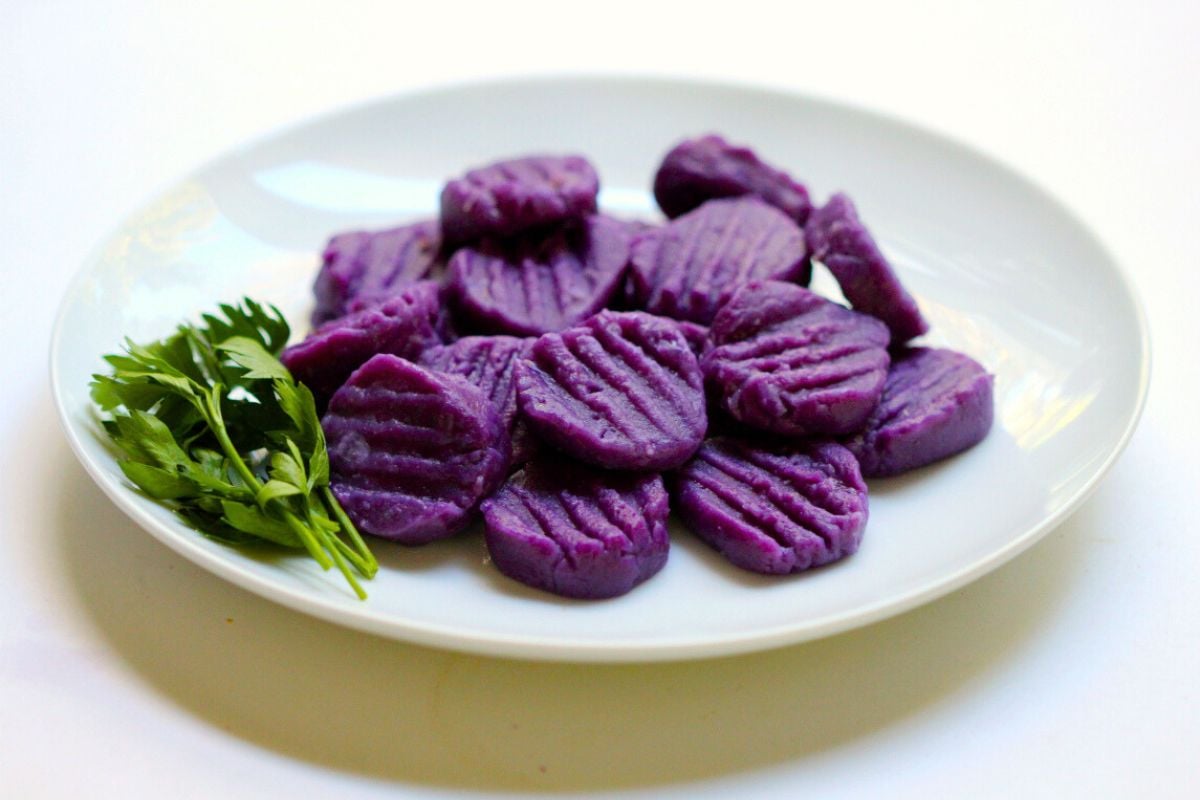 Purple Sweet Potato Gnocchi with Tahini Parsley Sauce served on a plate.