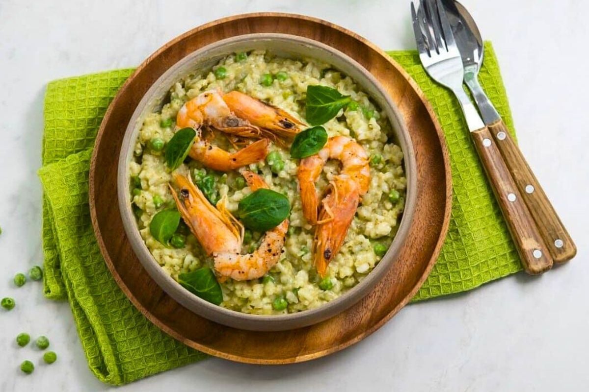 Risotto with Peas, Valerian and Prawns served on a plate.