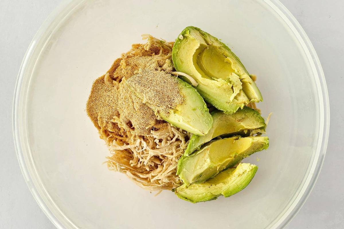 Ingredients for making avocado chicken salad in a bowl.