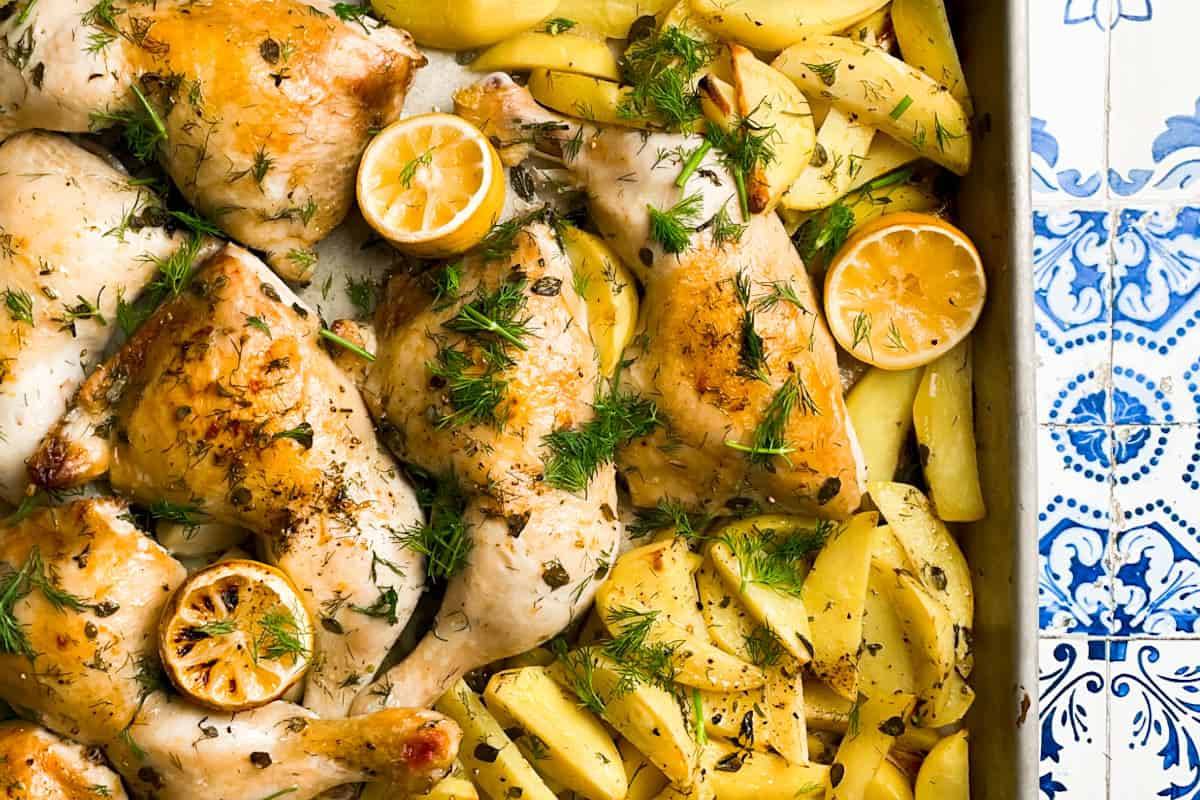 A sheet pan full of Greek lemon chicken and potatoes.