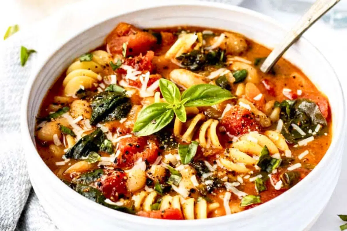 Italian White Bean Soup with Pasta with basil leaves on top.
