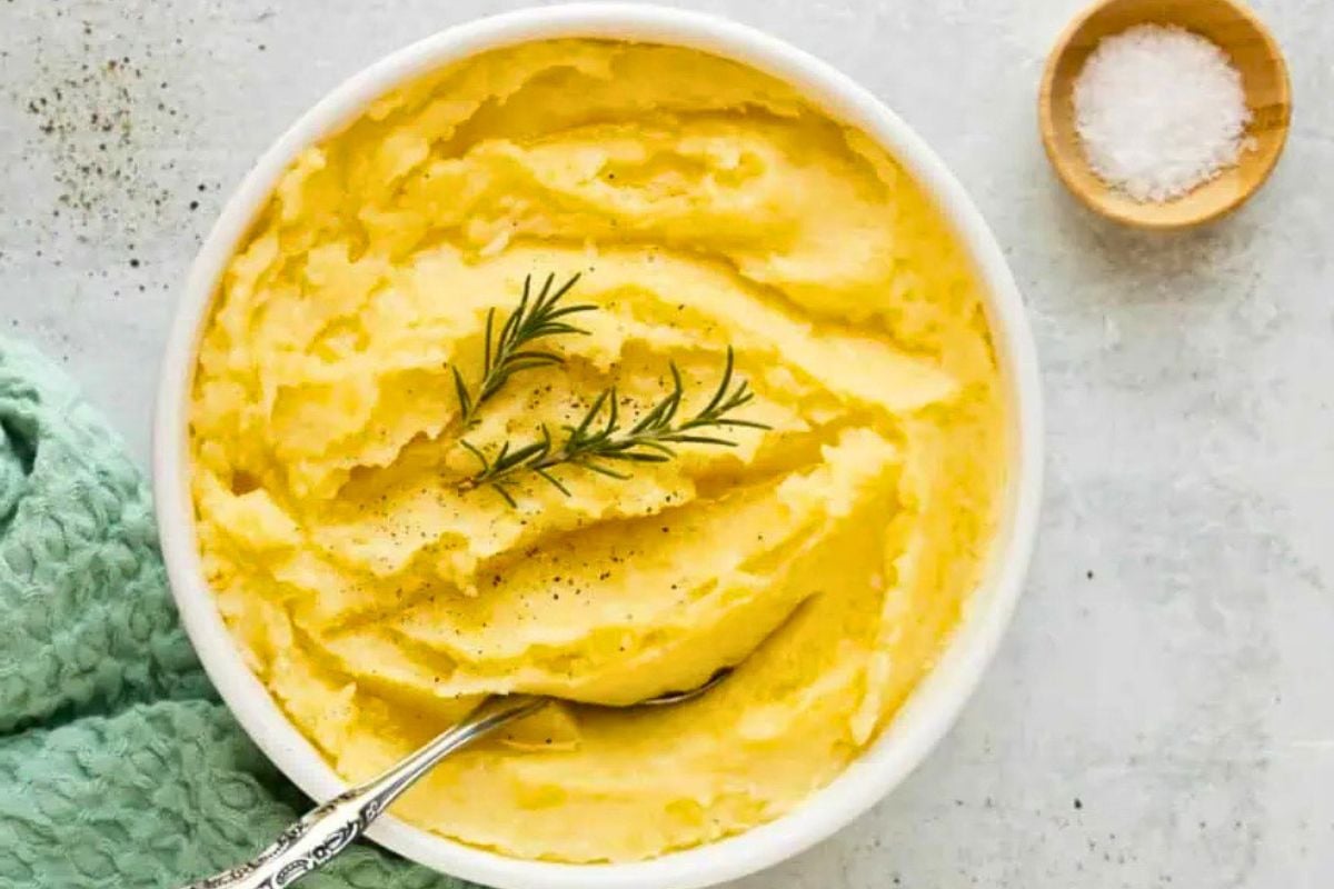 Mashed Potatoes garnished with rosemary leaves.