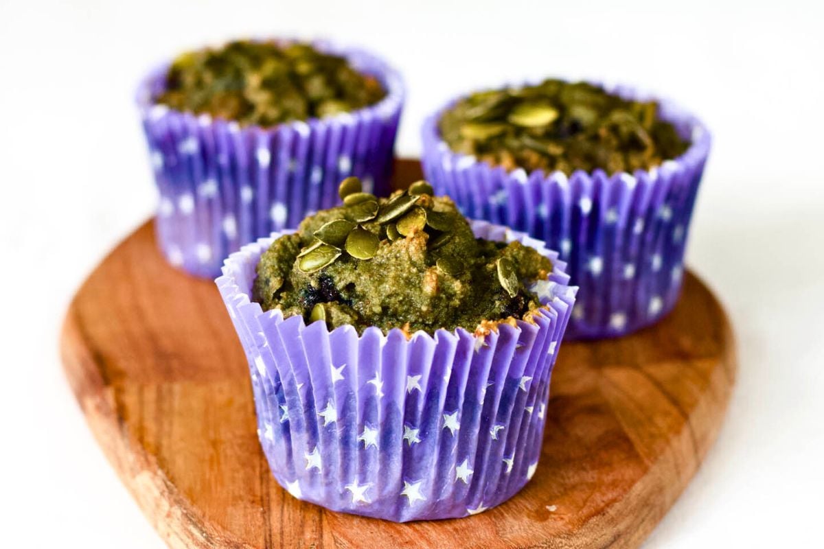 Pumpkin Seeds and Blueberries Keto Muffins on a wooden board.