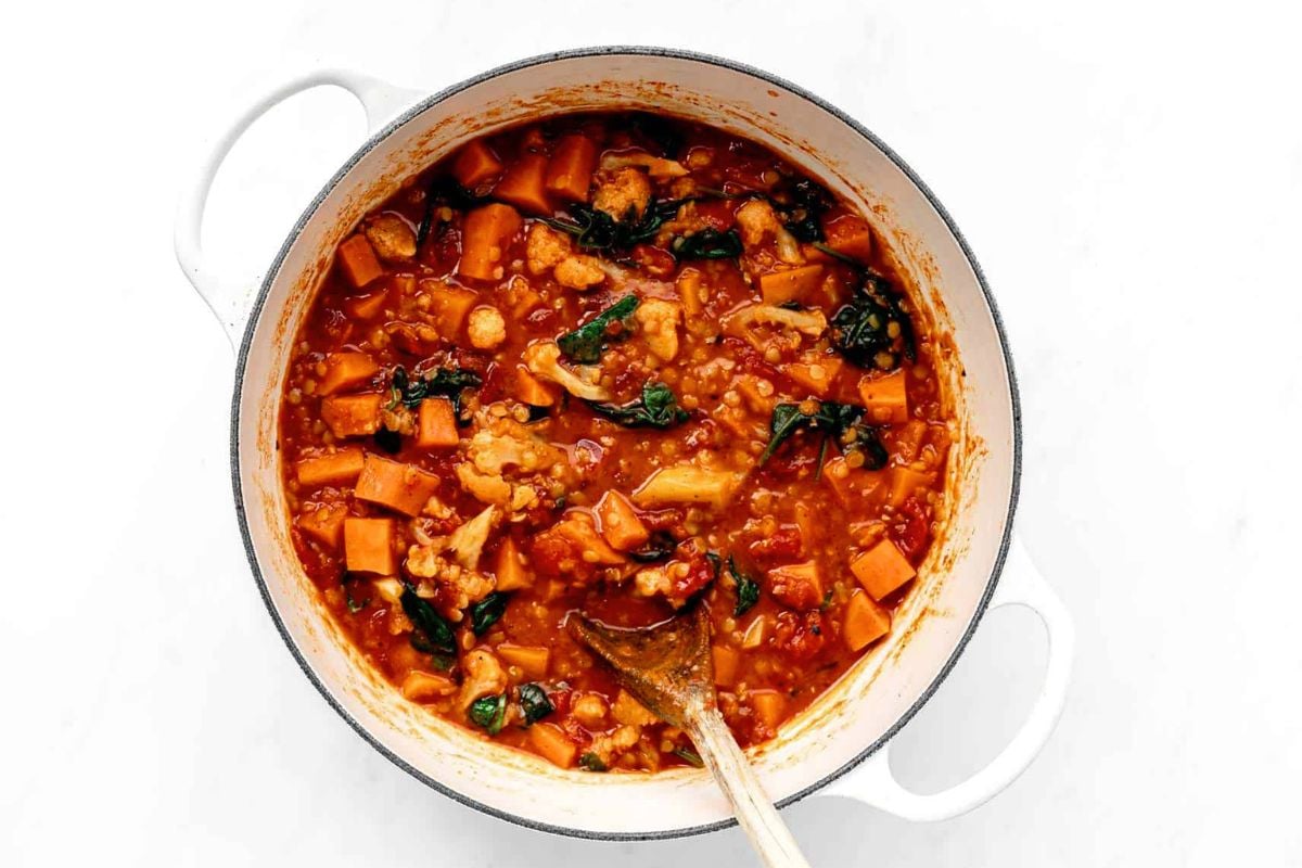 Red Curry Lentils with Sweet Potatoes and Spinach in a pot.