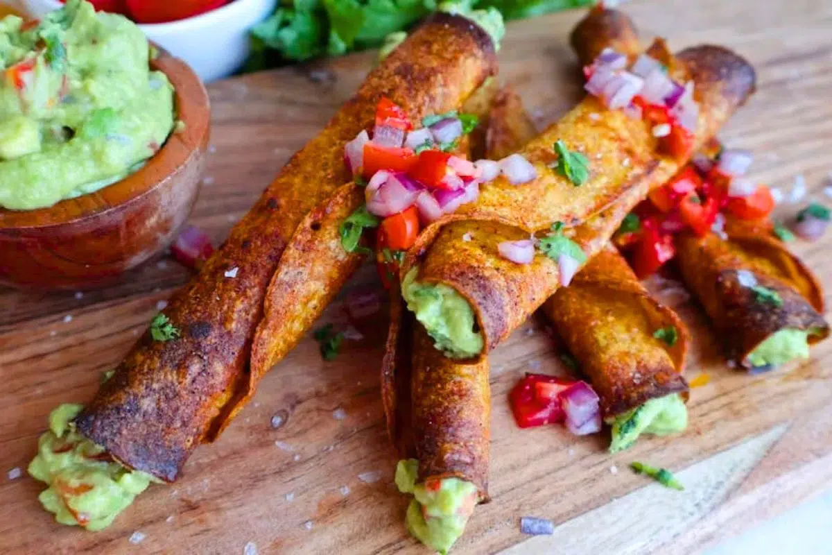 Vegan Taquitos with Guacamole on a wooden board.