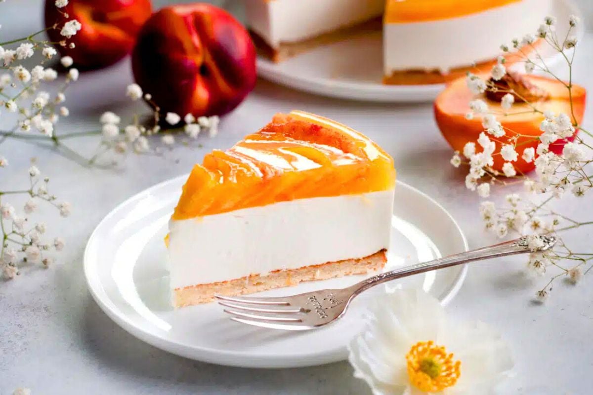 A slice of Layered Peach Yogurt Cake with Almond Base on a plate.