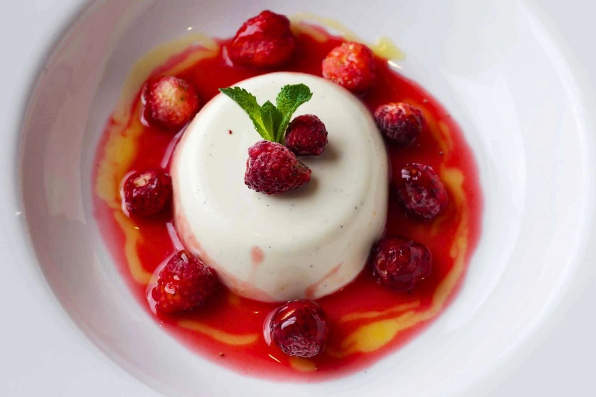Panna Cotta with Raspberries served on a plate.