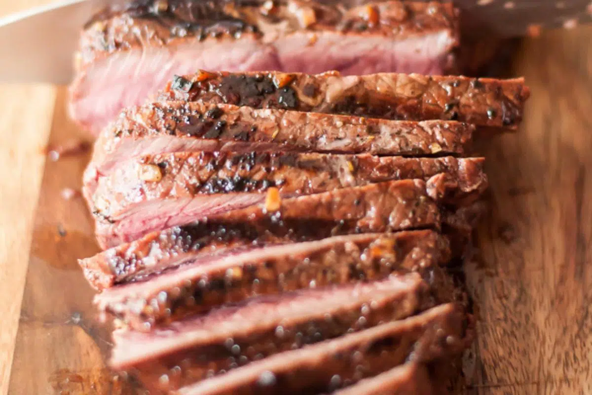 A sliced London broil on a cutting board.