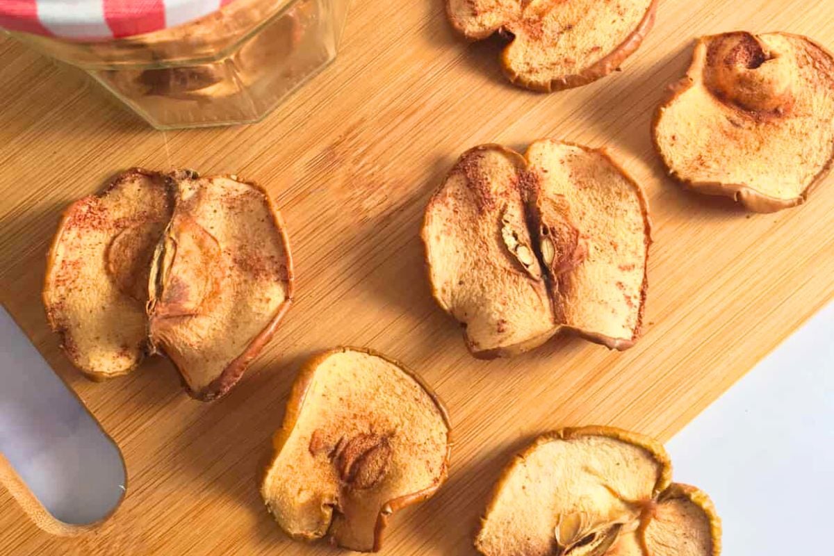 Dehydrated Cinnamon Apples on a wooden chopping board.