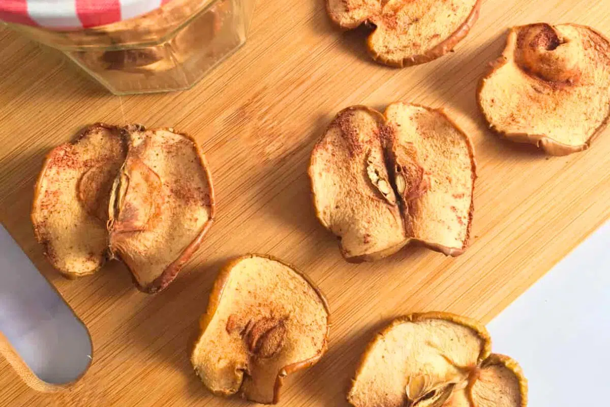 Dehydrated Cinnamon Apples on a wooden chopping board.