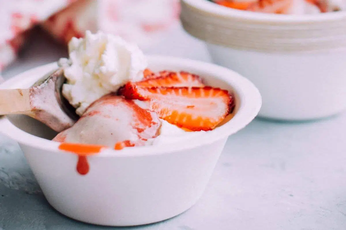 A bowl of banana ice cream with strawberries on top.