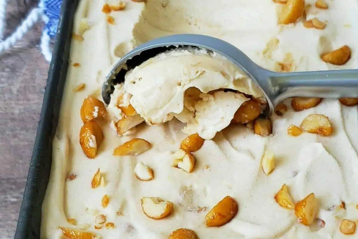An ice cream scoop scooping up peanut butter ice cream with peanute.