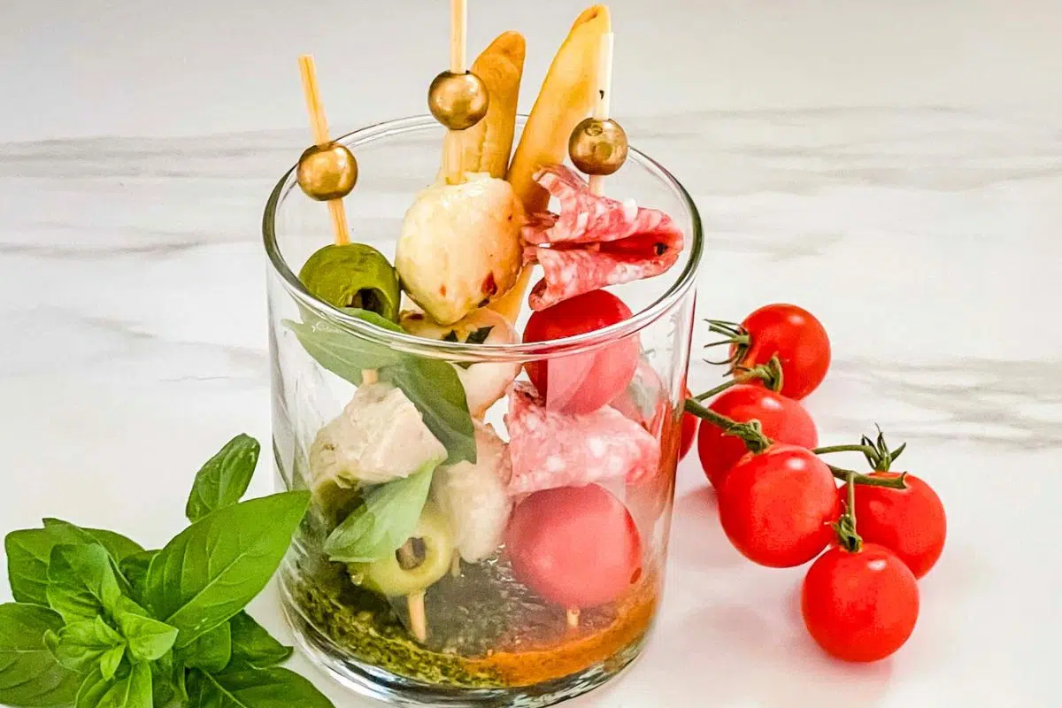 Individual Italian Charcuterie Cups with basil leaves and tomatoes.