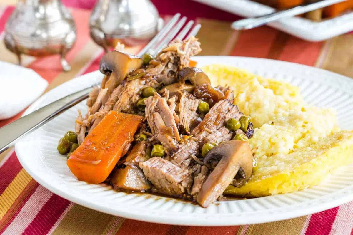 Pot roast on a white plate with potatoes.