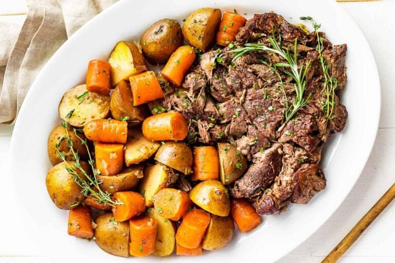 Pot roast and veggies on a white plate.