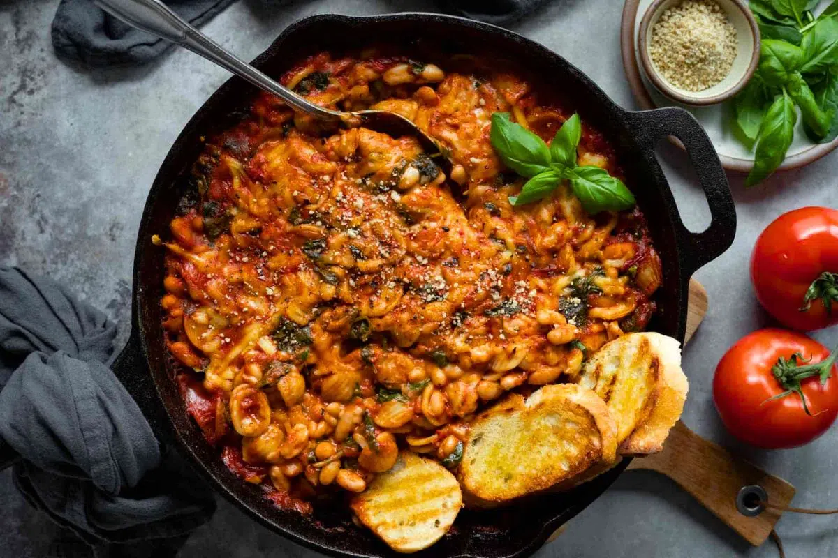 Tuscan White Bean Skillet Bake topped with basil leaves.