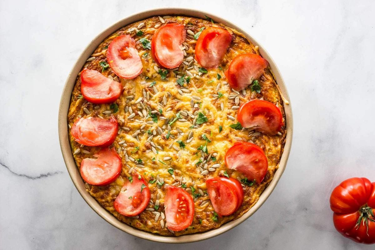 Crustless Zucchini Bacon Quiche topped with tomato slices.