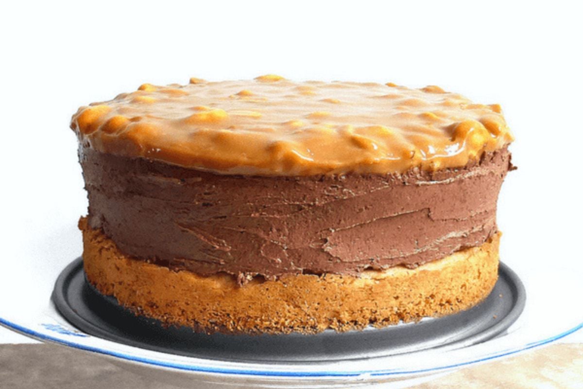 Chocolate Cheesecake with a Peanut Butter Cake Crust on a cake stand.