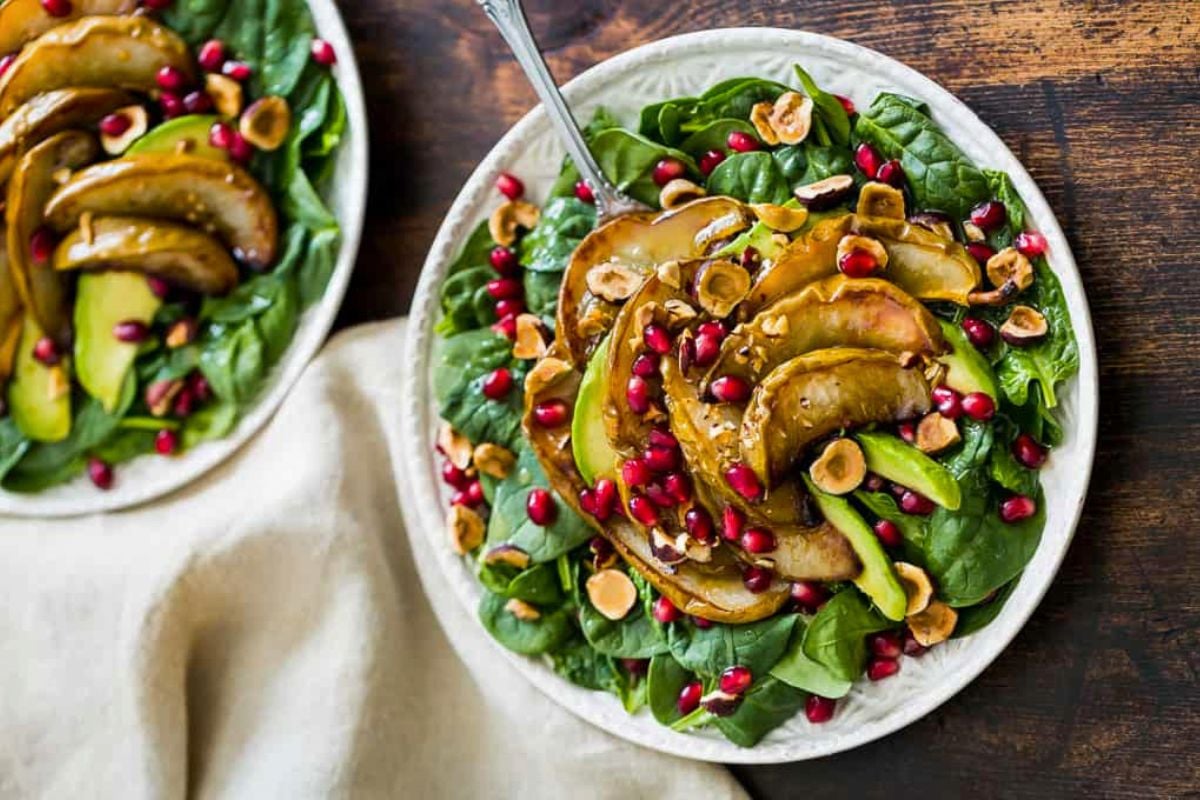 Roasted Pear Spinach Salad with Hazelnuts on a plate.