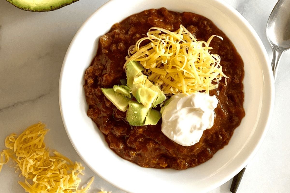 Slow Cooker No-Bean Chili garnished with avocado and cheese.